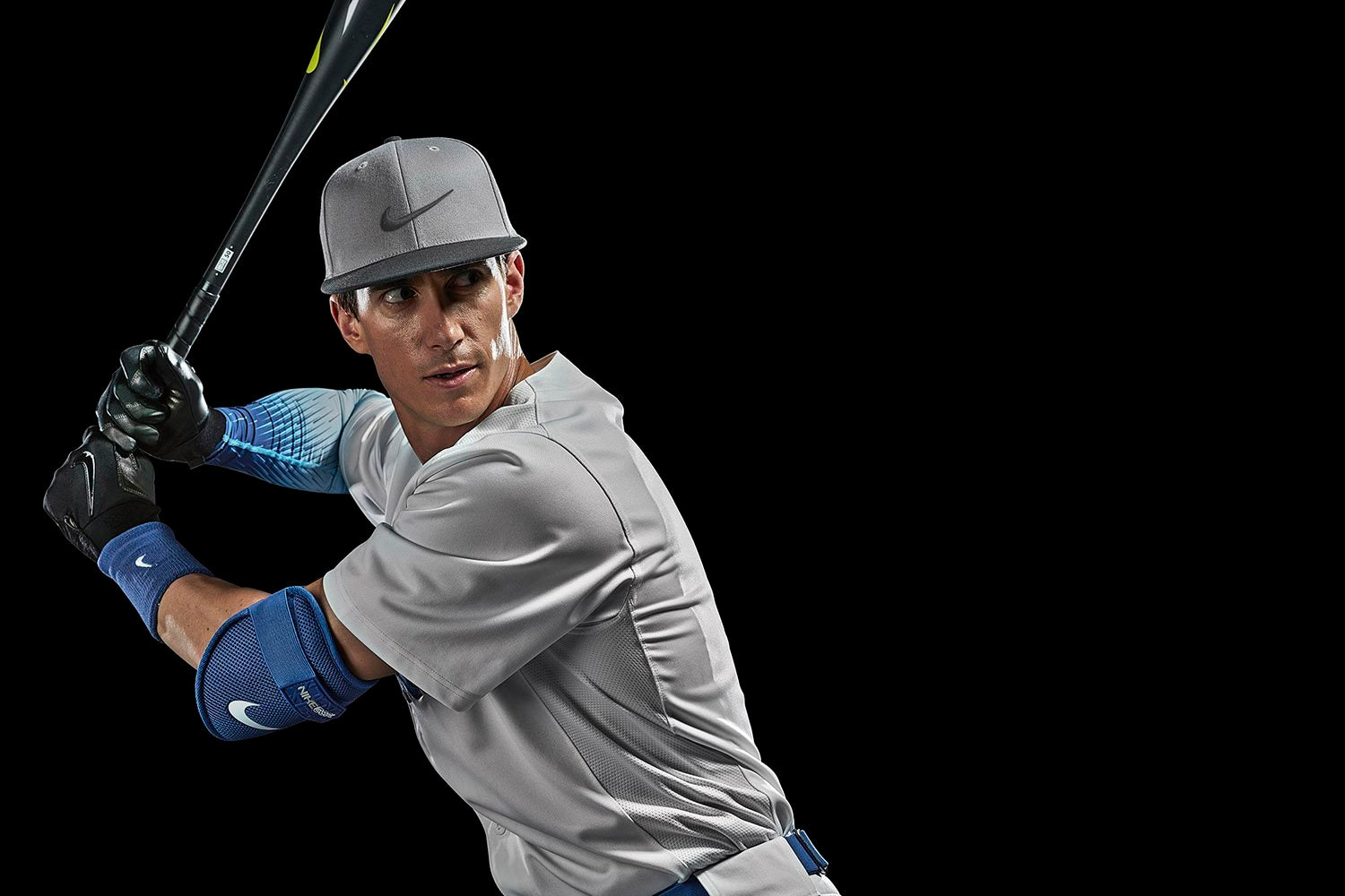 A baseball player with a bat, wearing Nike gear against a black background.