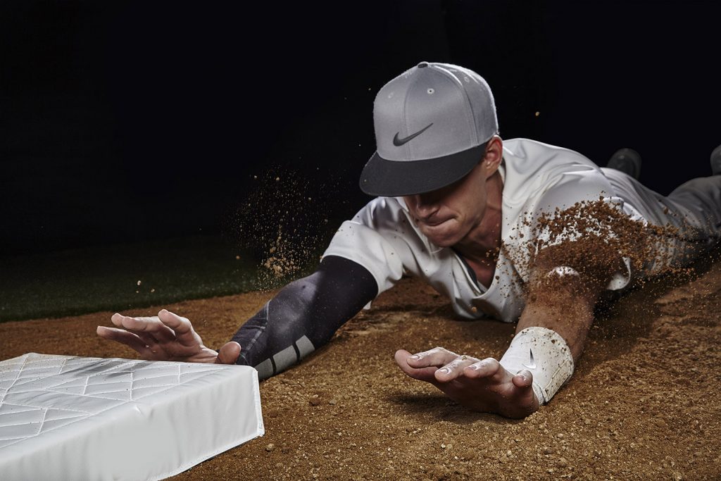 Baseball player sliding into a base, kicking up dirt.